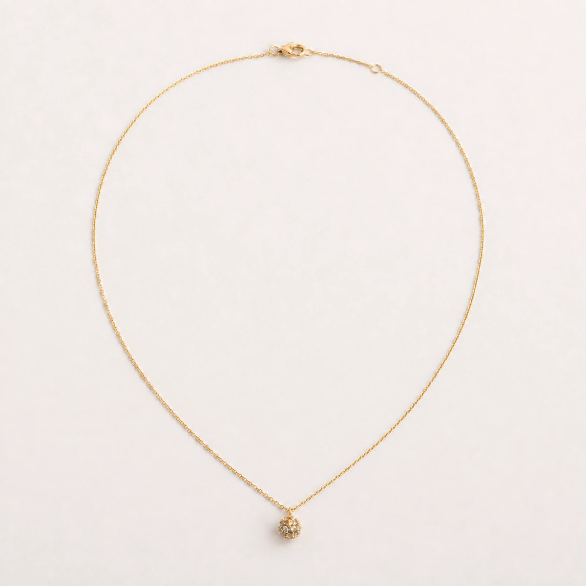Collar Semilla: cadena muy fina con dije pequeño e irregular.