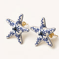 Aretes Jardín Azul: botón de cinco brazos con patrón floral azul sobre marfil.